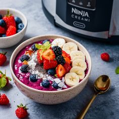 a bowl filled with fruit next to an electric crockpot on a counter top