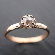 a gold ring with a white diamond in the center on a black surface, close up