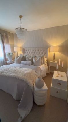 a large white bed sitting in a bedroom next to two lamps on either side of the bed