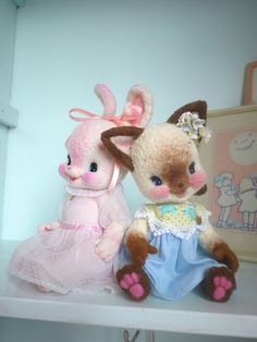 two stuffed animals sitting on top of a shelf