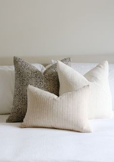 three pillows on top of a white bed