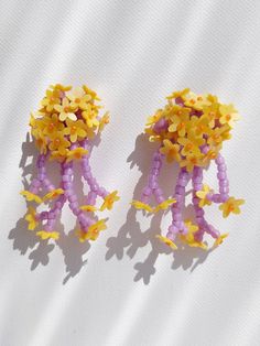 two small yellow and purple beads with flowers on them are sitting next to each other