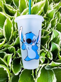 a starbucks cup with a cartoon character on it sitting in front of some green leaves