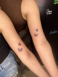 two women with matching tattoos on their arms, one is holding the other's arm