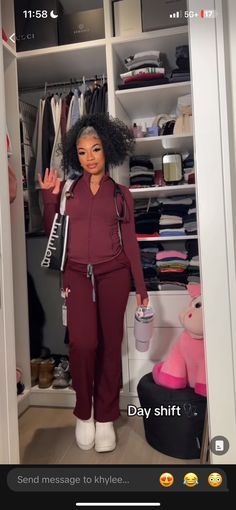 a woman standing in a closet with her hand up to the camera and wearing red pants