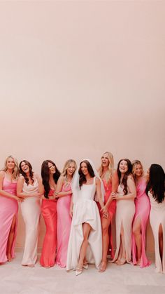 a group of women standing next to each other in long dresses and one woman wearing a white dress