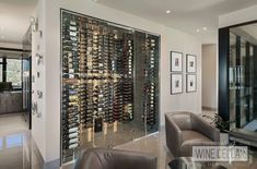 a wine cellar in the middle of a living room with two leather chairs and a glass table