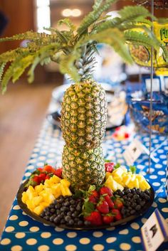 a pineapple sits on top of a platter of fruit