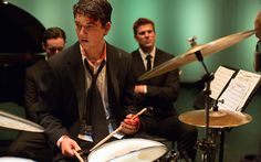 a man in a suit and tie playing drums