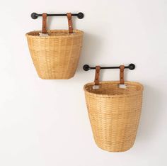 two baskets hanging on the wall, one with handles and another without handles for storage