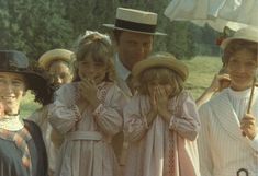 a group of people standing next to each other in front of a field with an umbrella