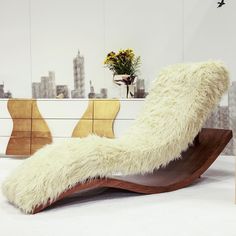 a white chair with long fur on it in front of a cityscape wall