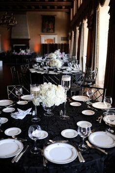 the tables are set with white flowers and black linens for an elegant dinner party