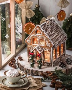 a gingerbread house with orange slices and cinnamons on the table next to it