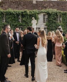 a group of people standing around each other in front of a building with ivy covered walls