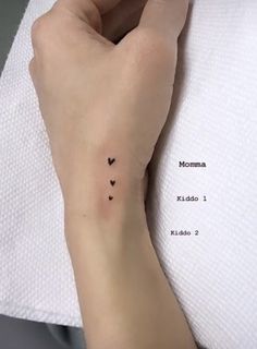 a woman's arm with two small hearts tattooed on the left side of her wrist