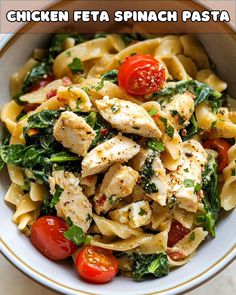 chicken feta spinach pasta in a white bowl with tomatoes and parmesan cheese