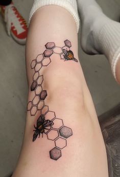 a tattoo on the leg of a woman with bees and honeycombs