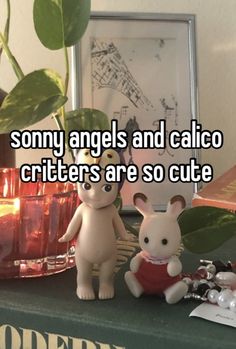 two stuffed animals sitting on top of a table next to a potted plant and candle