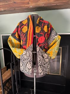 a colorful kimono sitting on top of a metal stand next to a fire place