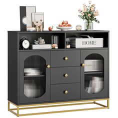 a black and gold sideboard with two doors, some plates and flowers on top