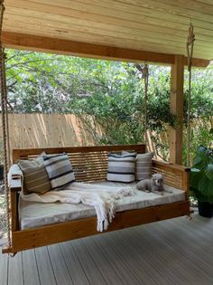 a wooden porch swing with pillows on it