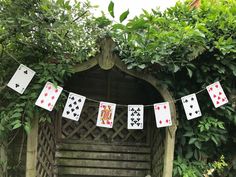 playing cards are hung on a clothes line in front of an old wooden structure with ivy growing around it