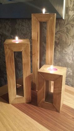 three wooden frames with candles in them on a table