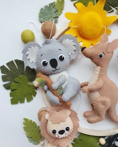 three stuffed animals are hanging from a hoop with leaves and sunflowers in the background