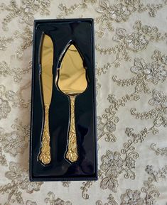 a black box with gold colored utensils in it on a white tablecloth