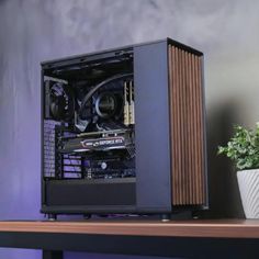 a computer case sitting on top of a wooden desk next to a plant in a pot