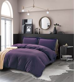 a bed with purple sheets and pillows in a room