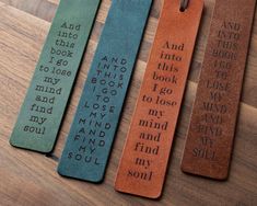 three bookmarks with words on them sitting on a wooden table next to each other