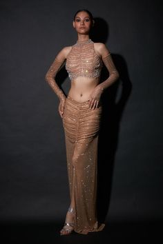 a woman in a gold dress posing for the camera with her hands on her hips