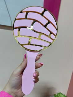 a hand holding a pink and gold mirror