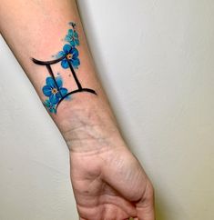 a person's arm with a blue flower tattoo on it and the letter t