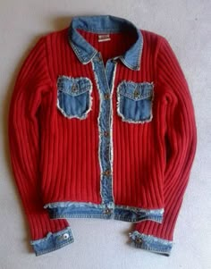 a red and blue sweater with fraying on the front, sitting on a white surface