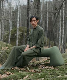 a man sitting on top of a pile of leaves in the middle of a forest