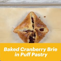 baked cranberry brie in puff pastry on parchment paper with text overlay reading baked cranberry brie in puff pastry