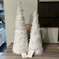 two white christmas trees sitting on top of a wooden table