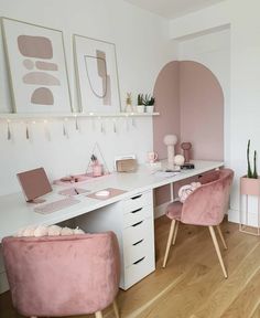 a white desk topped with pink chairs next to a wall mounted art work area and potted plants