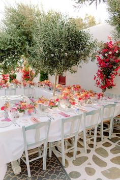 an outdoor dining area with white table cloths and pink flowers