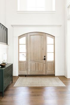 an entryway with two wooden doors and a rug on the floor in front of it