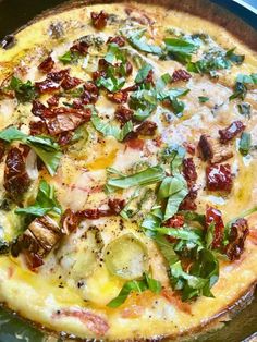 a pizza sitting on top of a pan covered in cheese and toppings with green leaves