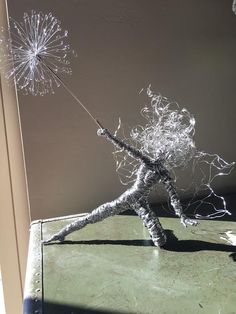 a wire sculpture of a person holding a dandelion