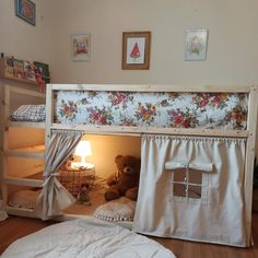 a teddy bear sitting in the bottom bunk of a child's bed with curtains