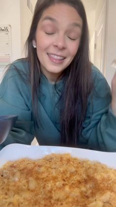 a woman sitting at a table with a plate of food in front of her smiling