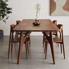 a wooden table with chairs around it and a potted plant in the corner next to it