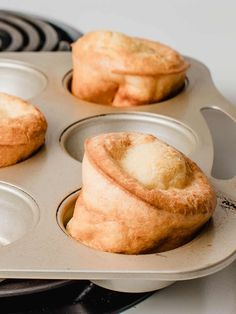 three muffins sitting in a metal pan on top of a stove burner