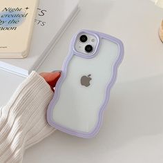 someone holding an iphone case in their hand on a white table next to a book